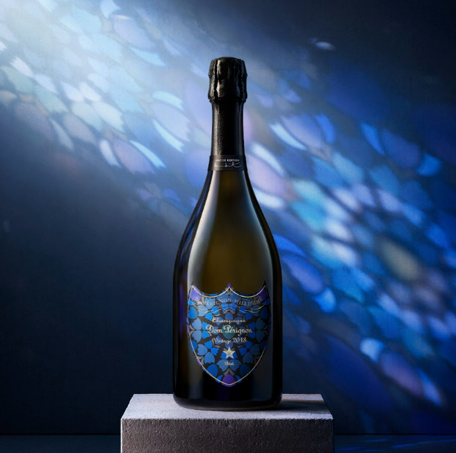 Garrafa de champanhe Dom Pérignon 2018 com rótulo blue e fundo azul brilhante.